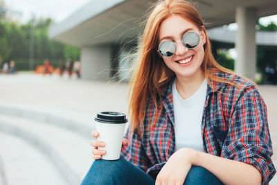 Portrait of smiling young woman holding while sitting outdoors