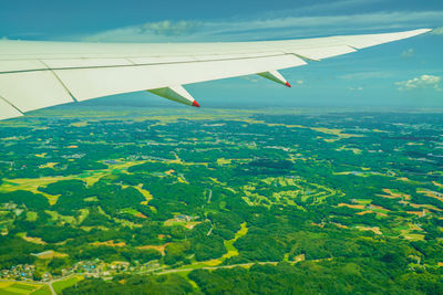 Airplane flying over landscape against sky