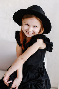 Portrait of smiling girl wearing hat standing against white background