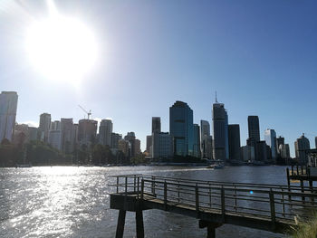 Modern buildings by river against sky in city