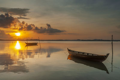 Boat moored in sea against sky during sunset