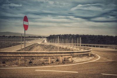 Road passing through landscape against cloudy sky