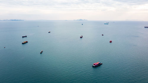 Aerial seascape view and small container ship floating in sea horizon and cloud sky background 