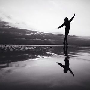 Silhouette of woman jumping in sea