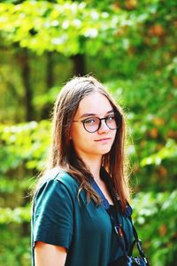 Portrait of young woman standing against plants