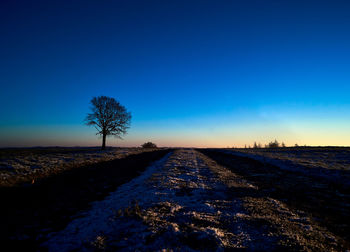 Scenic view of snowy field against clear blue sky during winter