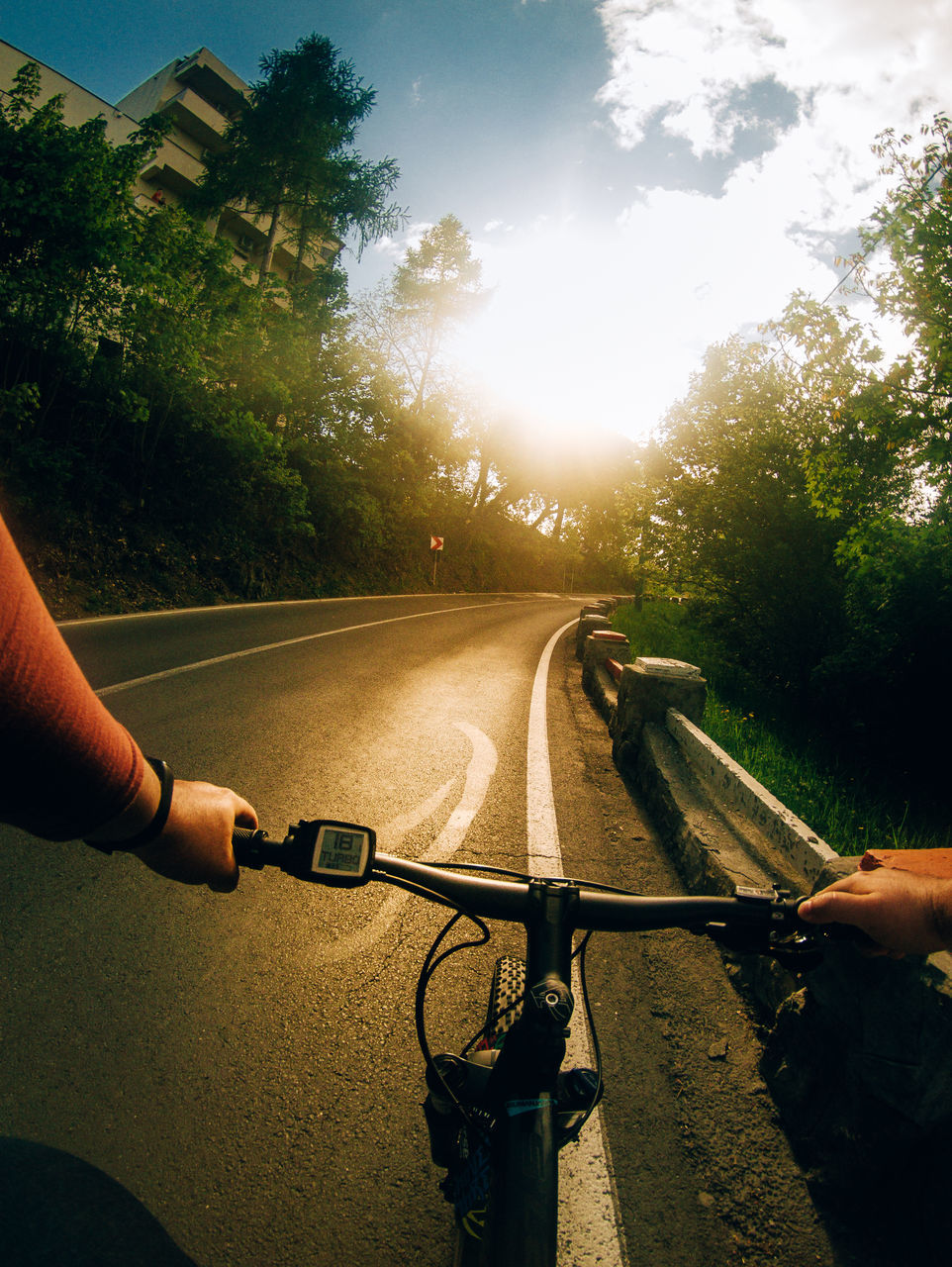 PERSON RIDING BICYCLE ON ROAD AGAINST SKY