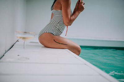 Low section of woman standing by swimming pool