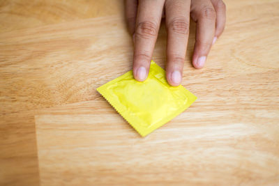 Close-up of man holding condom on table