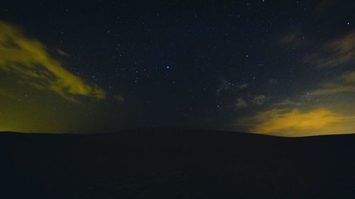 Scenic view of landscape against star field at night