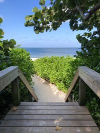 Wooden walkway by sea against sky