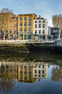 Reflection of buildings on river against sky