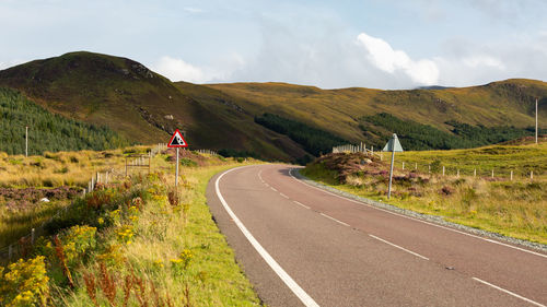 Road passing by mountain against sky