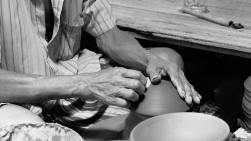 Midsection of man working on pottery wheel at workshop