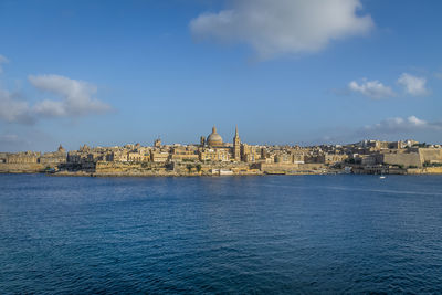 Buildings by sea against sky