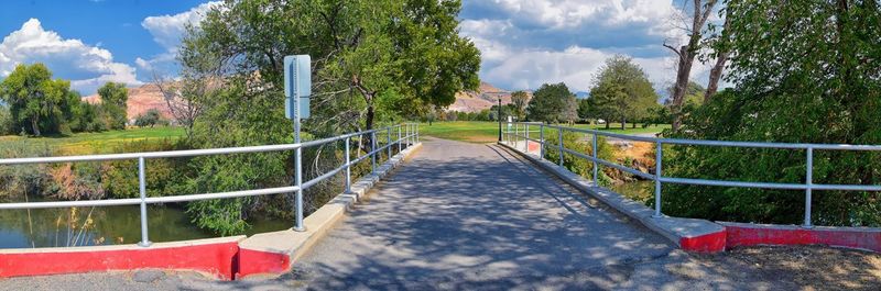 Footbridge amidst trees against sky