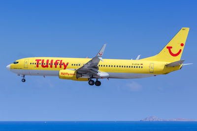 Airplane flying over sea against clear sky