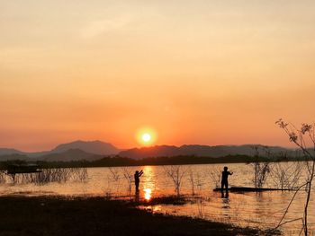 Silhouette person on shore against sky during sunset