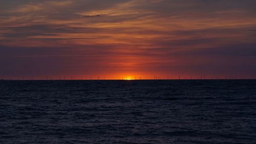 Scenic view of sea against dramatic sky during sunset
