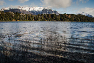 Scenic view of lake by snowcapped mountains against sky