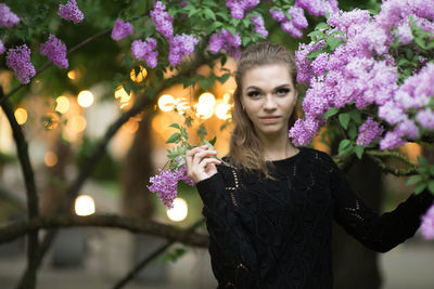 Portrait of young woman by purple flowers on branches