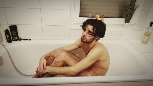 Young man sitting in bathroom