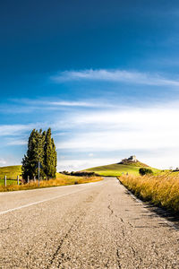 Surface level of road amidst field against sky