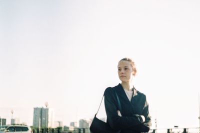 Portrait of a young woman with cityscape against sky