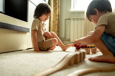 Two brothers play toys, they build a railway from a wooden construction set