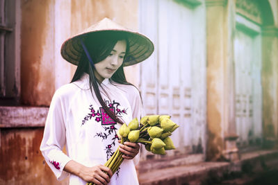 Vietnamese woman in traditional clothing holding flowers