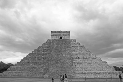 People in front of historical building against cloudy sky