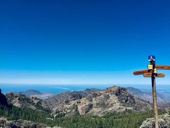 View of cross on mountain against blue sky