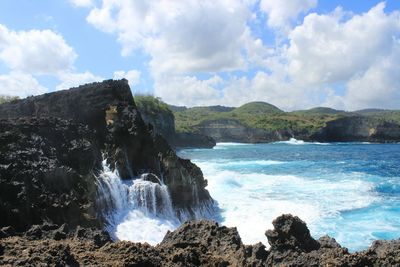 Scenic view of waterfall by sea against sky
