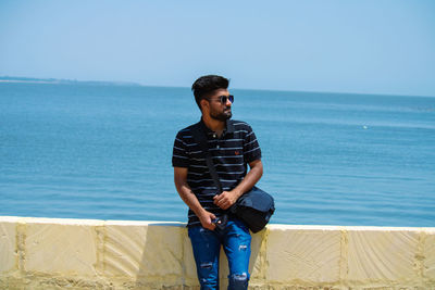 Young man standing in sea against sky