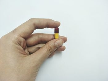 Close-up of hand holding cigarette over white background