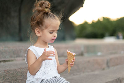 Cute girl eating ice cream while sitting on steps