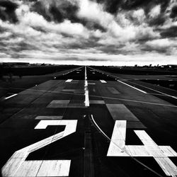 Road sign on airport runway against sky