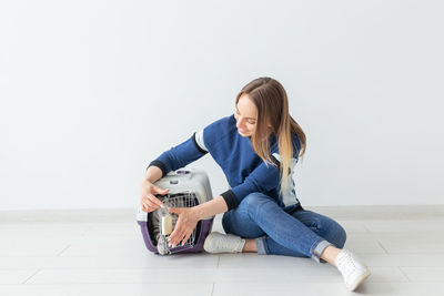 Full length of woman sitting on floor against white background