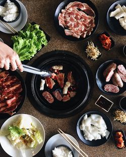 Cropped image of hand preparing meat on barbecue grill