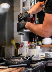 Cropped hands of man seasoning food in kitchen