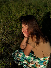 Smiling woman crouching on field