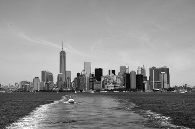 Sea by cityscape against sky