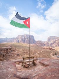 Jordanian flag on rocky mountain against sky
