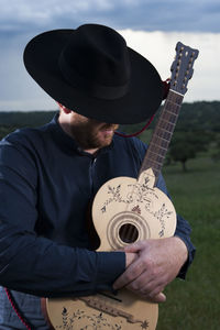 Man with guitar standing against sky