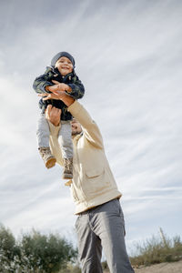 Happy boy enjoying with father in front of sky at beach