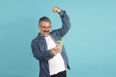 Portrait of young man standing against blue background
