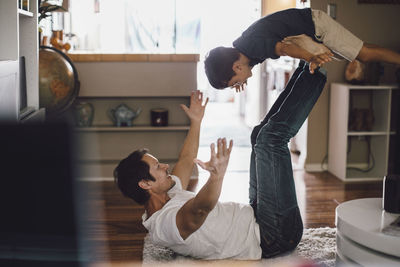 Happy father playing while holding son in mid-air on legs