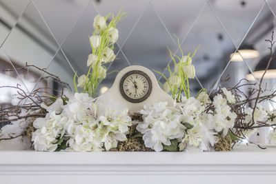 Clock with white flowers against patterned mirror