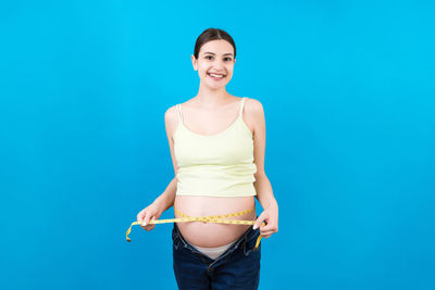 Portrait of a smiling young woman against blue background