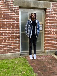 Portrait of young man standing against door